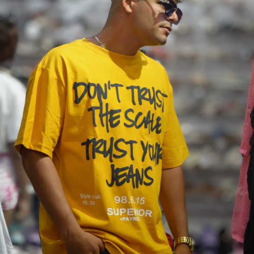 Camiseta amarilla con la frase "DON'T TRUST THE SCALE TRUST YOUR JEANS" (No confíes en la báscula, confía en tus jeans).