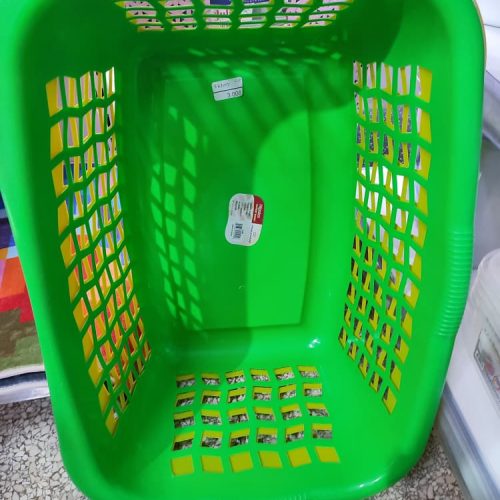 Cesta de la ropa de plástico de color verde, comúnmente utilizada para almacenar y transportar ropa sucia o limpia